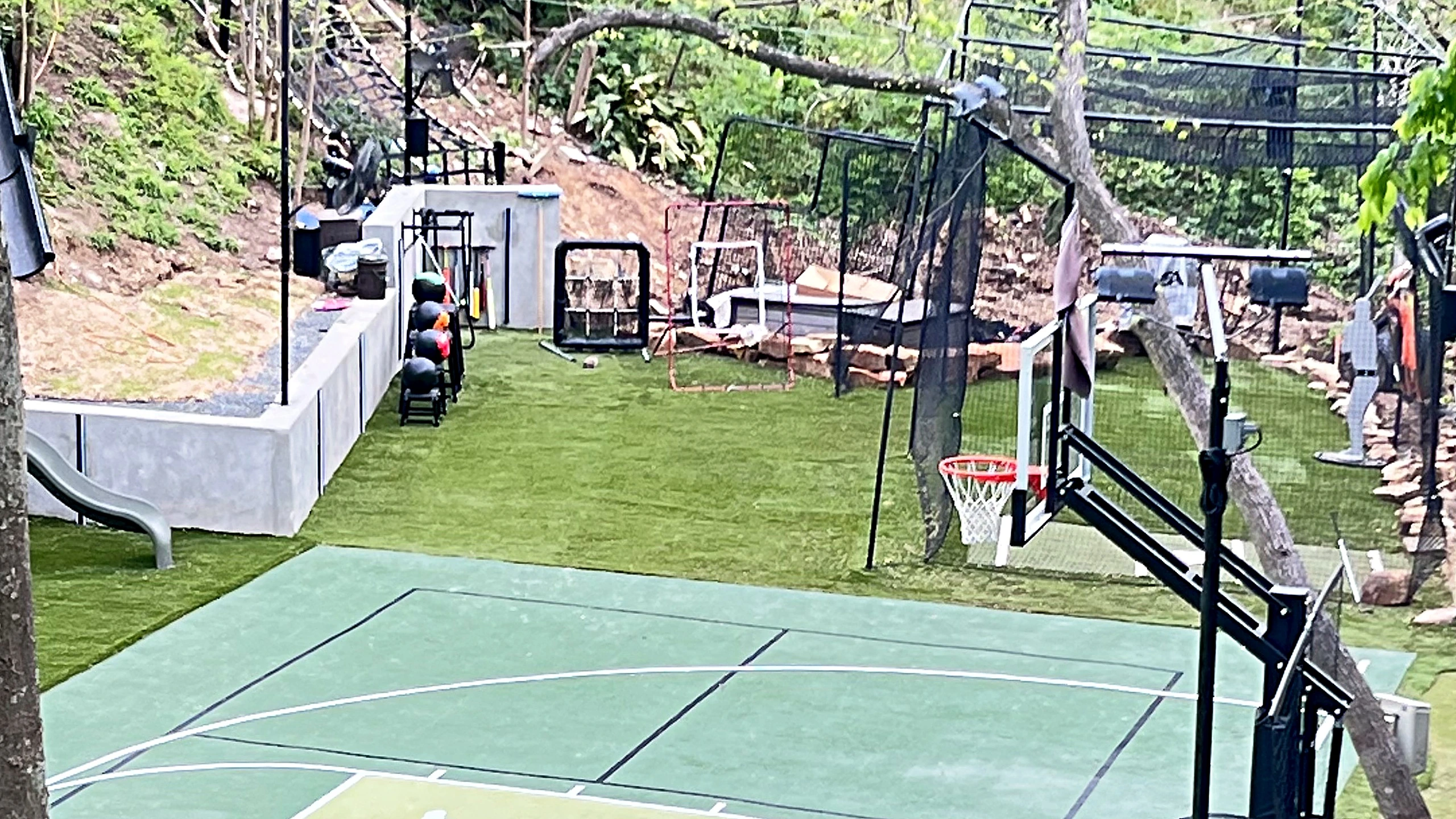 Daytime aerial of finished multi-sport court with basketball and pickleball markings and synthetic turf surround