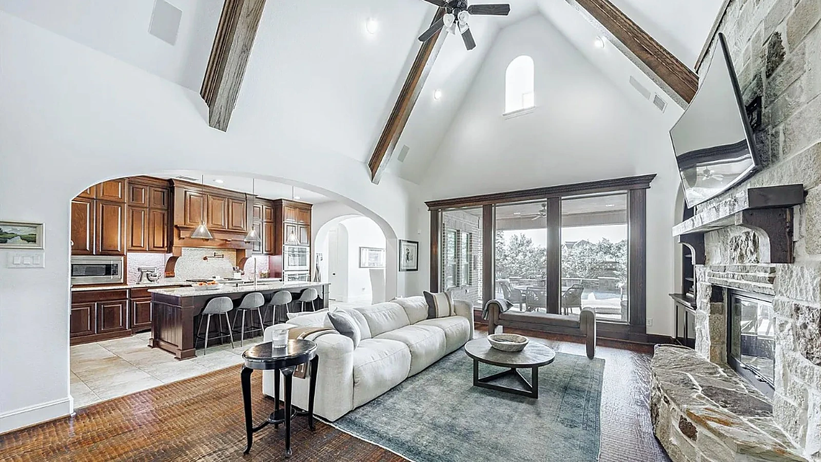 Completed whole-home interior renovation in Bellaire Houston showing vaulted great room, stone fireplace, and curved staircas