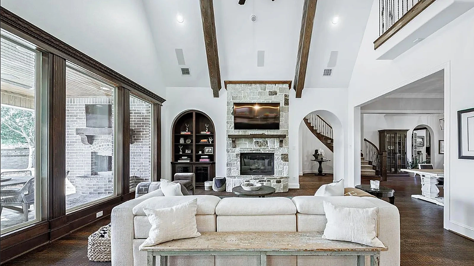 Floor-to-ceiling natural stone fireplace wall with wood beams in great room of Bellaire Houston home remodel