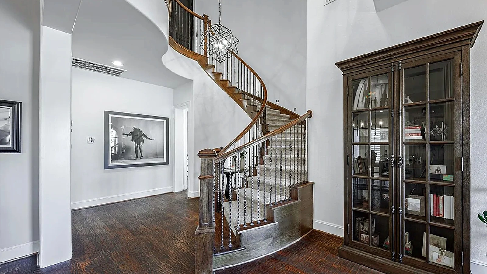 Arched built-in shelving and open plan living with dark hardwood floors in Bellaire interior renovation