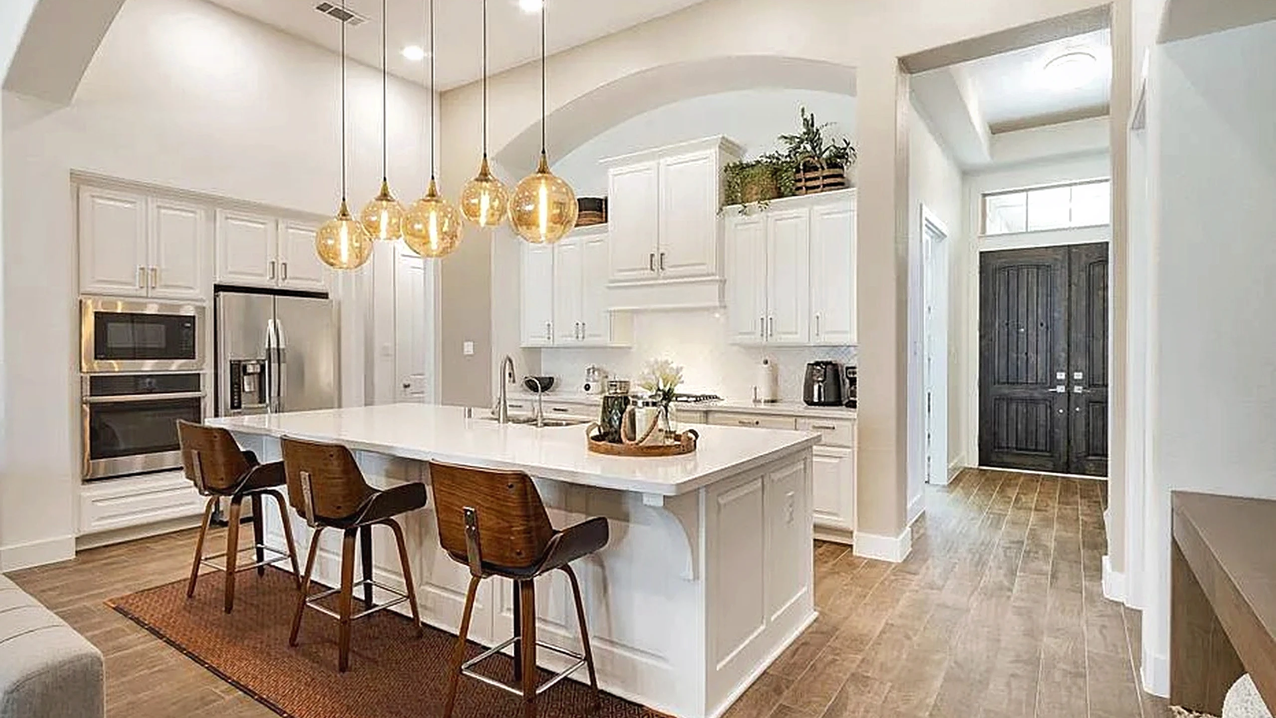 Cypress home remodel featuring white cabinetry, wood-look flooring, and an arched passage between the kitchen and living area