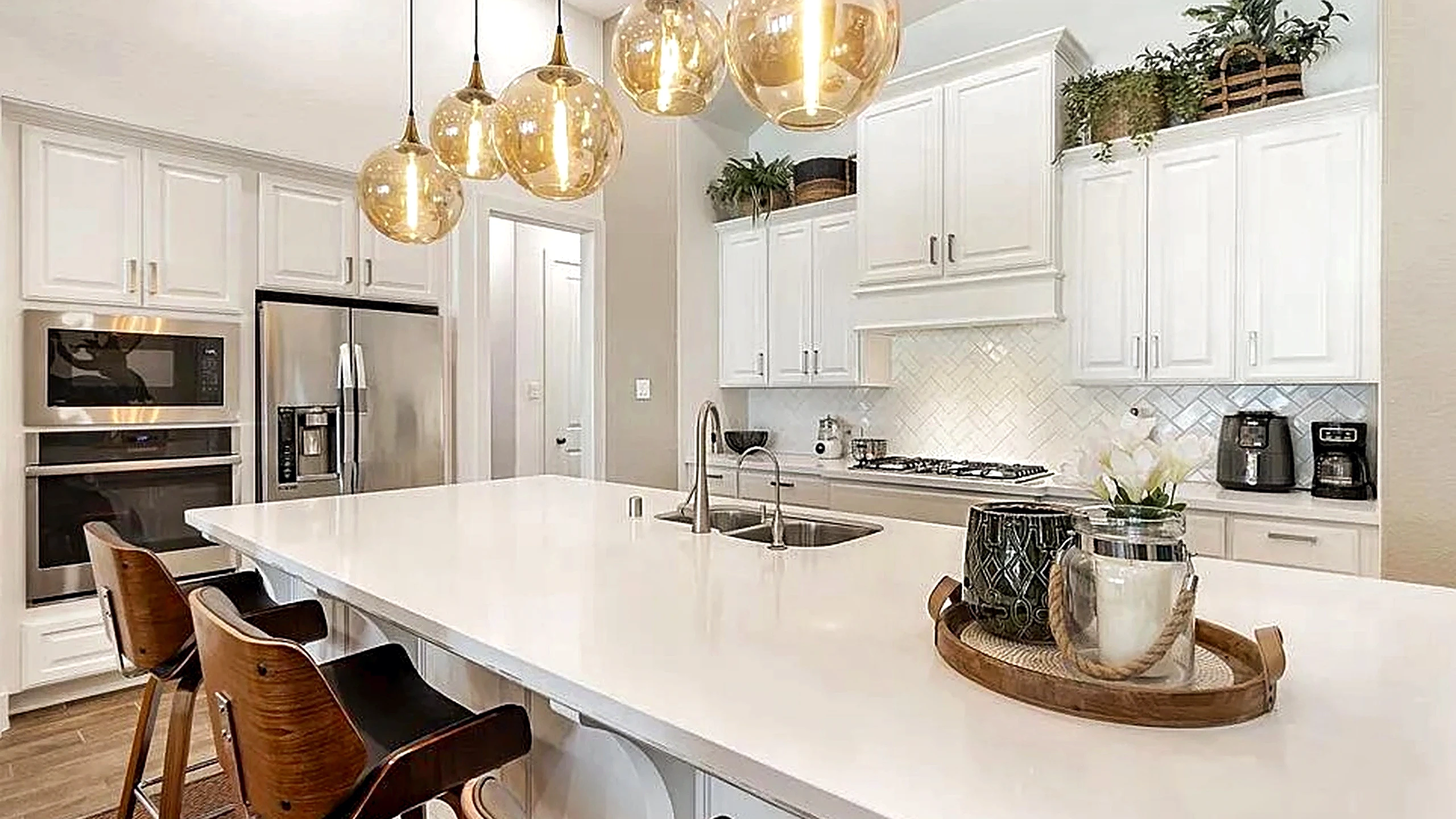 Cypress home kitchen remodel with white cabinetry, wood-look flooring, and an arched passage leading to the living area.