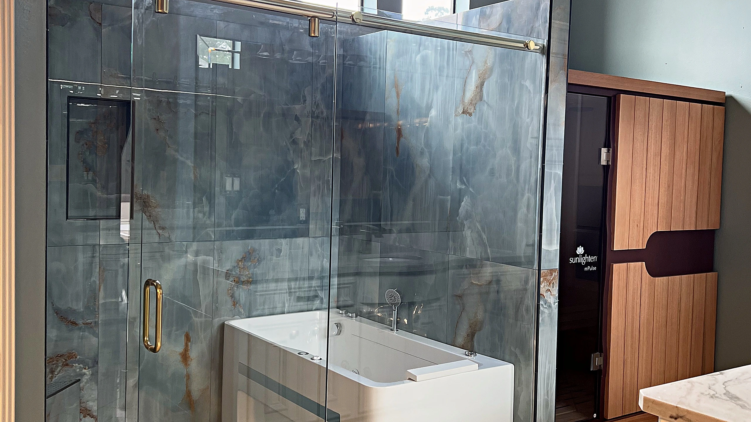 Finished master bathroom renovation in Bunker Hill Village featuring natural stone surfaces, frameless glass shower, and warm