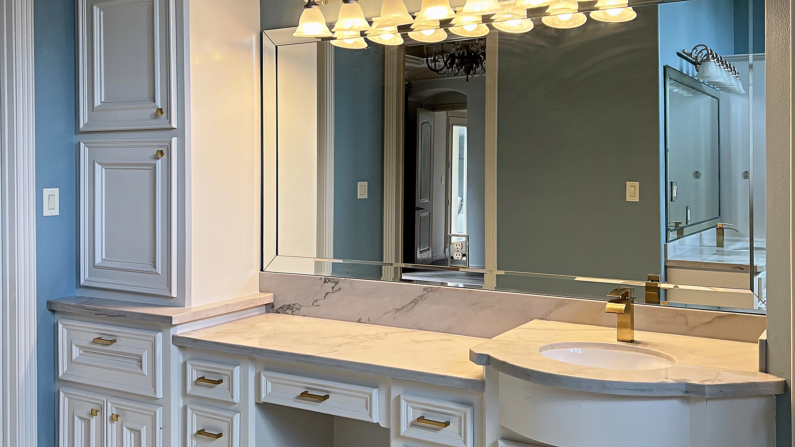 Finished master bathroom in Bunker Hill Village with natural stone surfaces, frameless glass shower, and warm metal finishes