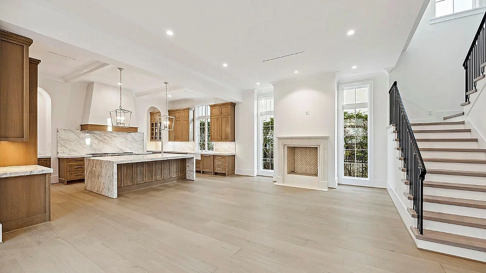 Wide-plank wood foyer floor with paneled accent wall and curved staircase descending to entry hall