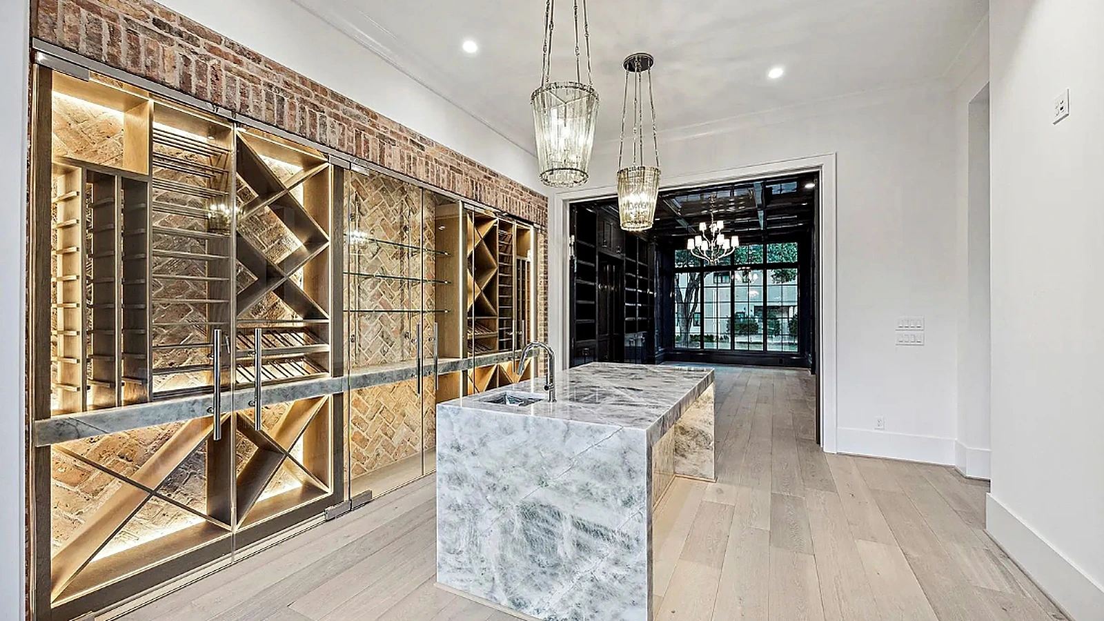 Open-plan kitchen and living room with natural stone island, warm wood cabinetry, and stone fireplace with herringbone tile