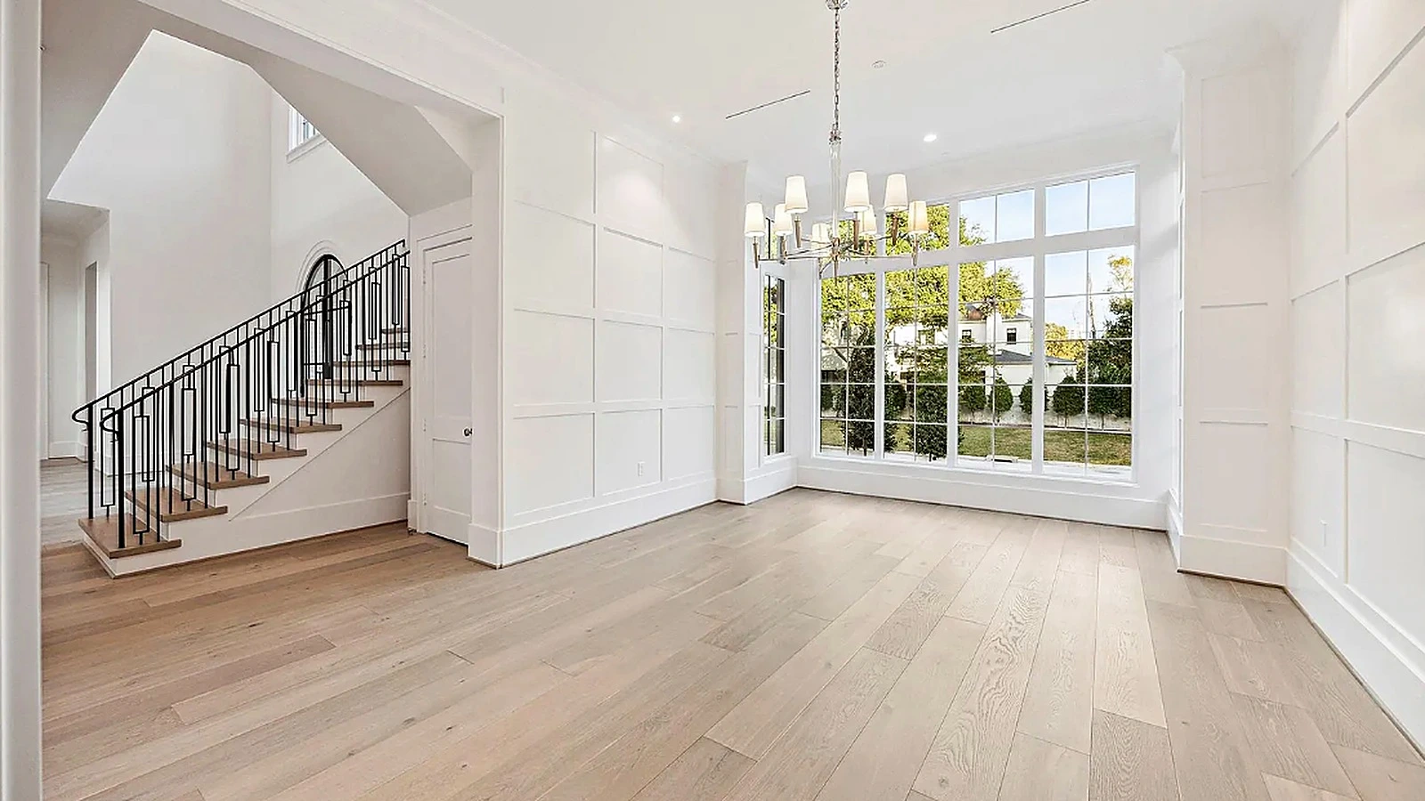 Natural stone waterfall island and plastered range hood in wide open-plan kitchen with wide-plank wood floors