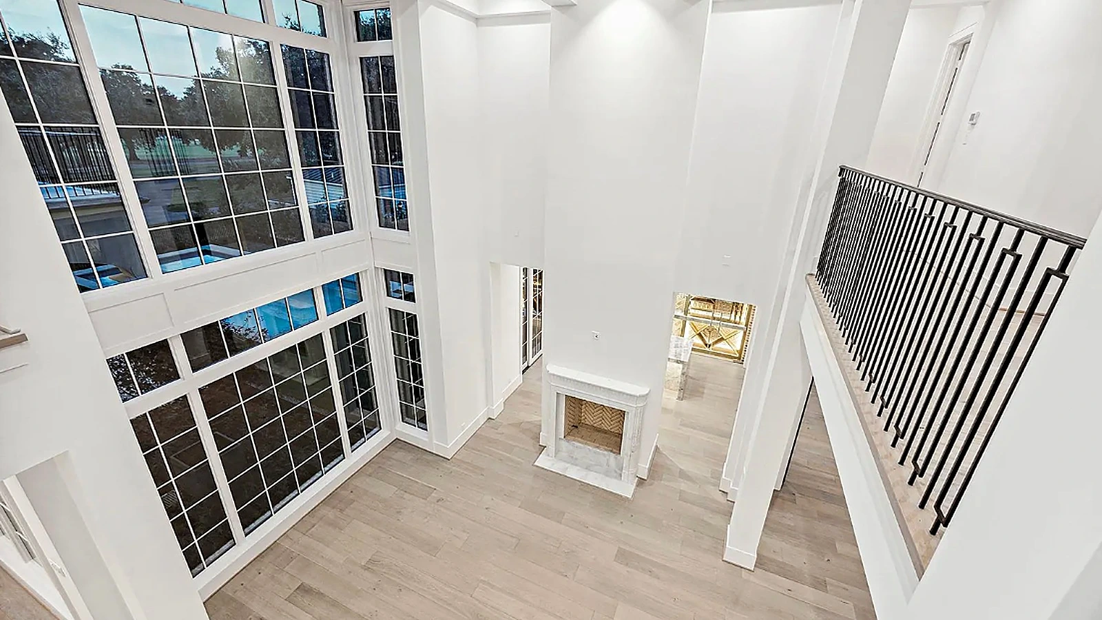 Dark-shelved study visible through steel-framed glazing beyond the wine room, lit by a traditional chandelier