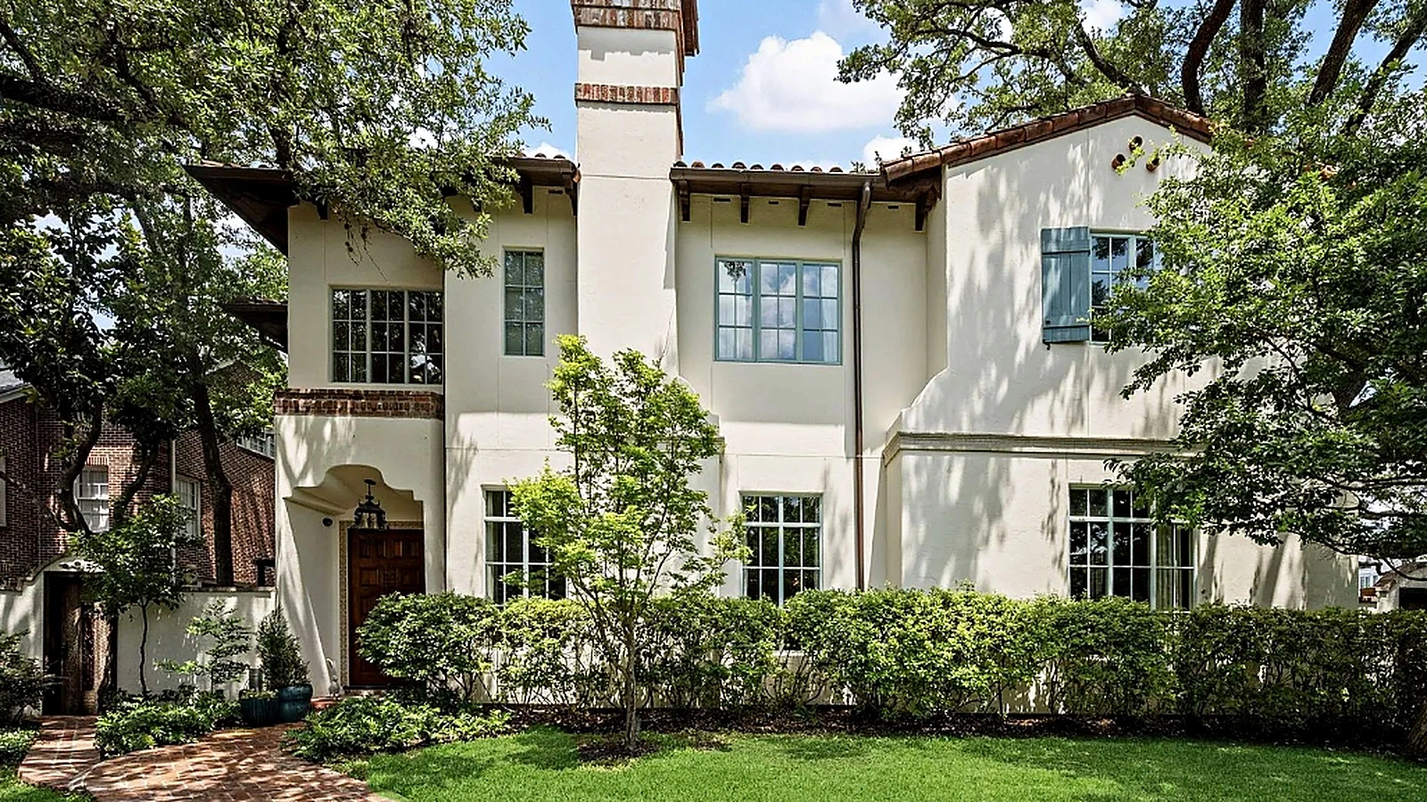 Restored two-tone stucco exterior with clay tile roof and arched entry in Hunters Creek Village after Bager Remodeling projec