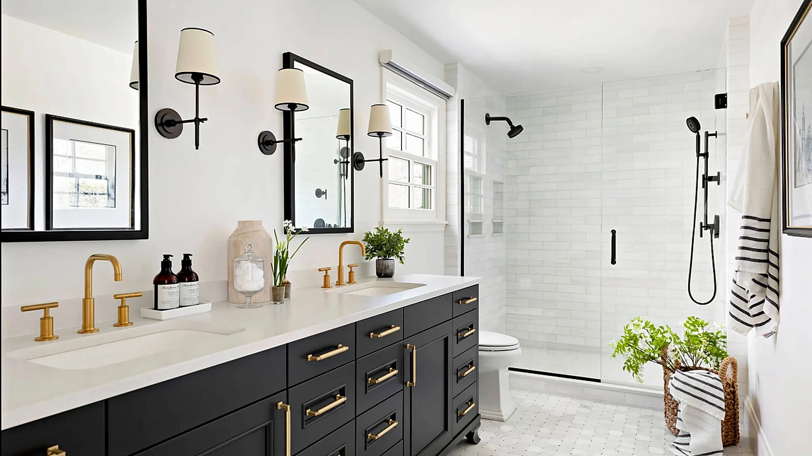 Double-sink bathroom vanity with dark cabinetry, white stone countertop, brass fixtures, and black-framed mirrors