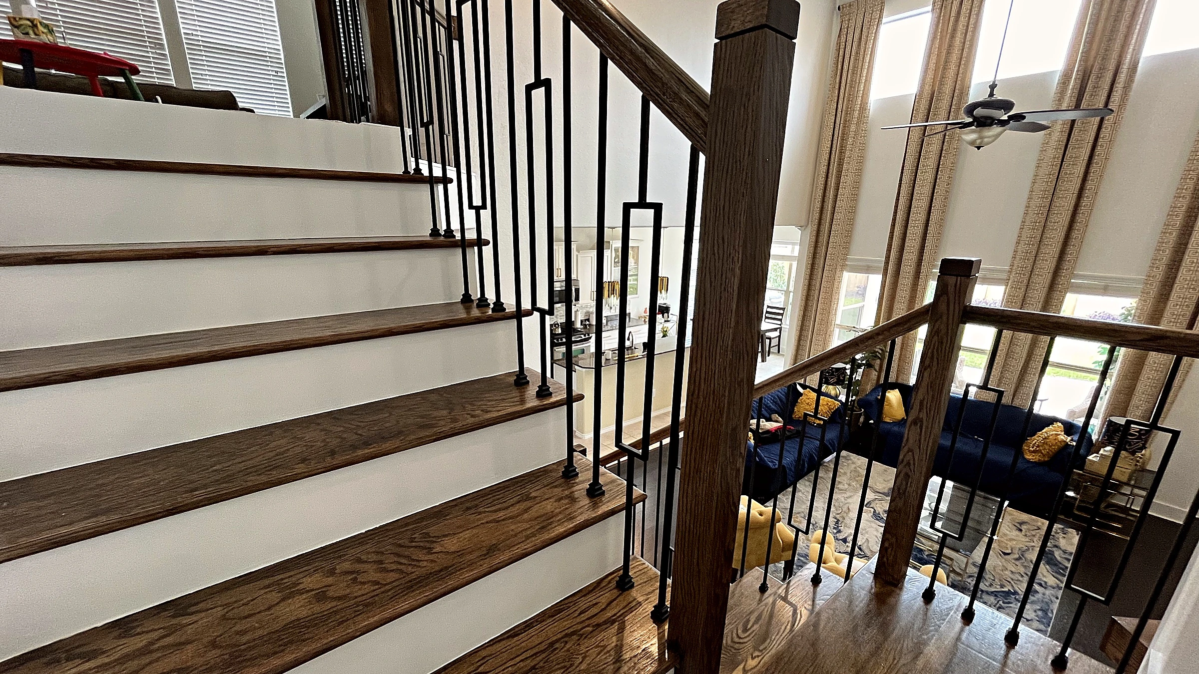 Dark-stained wood stair treads and painted risers with rectangular-loop iron balusters and wood newel post, Fulshear home rem