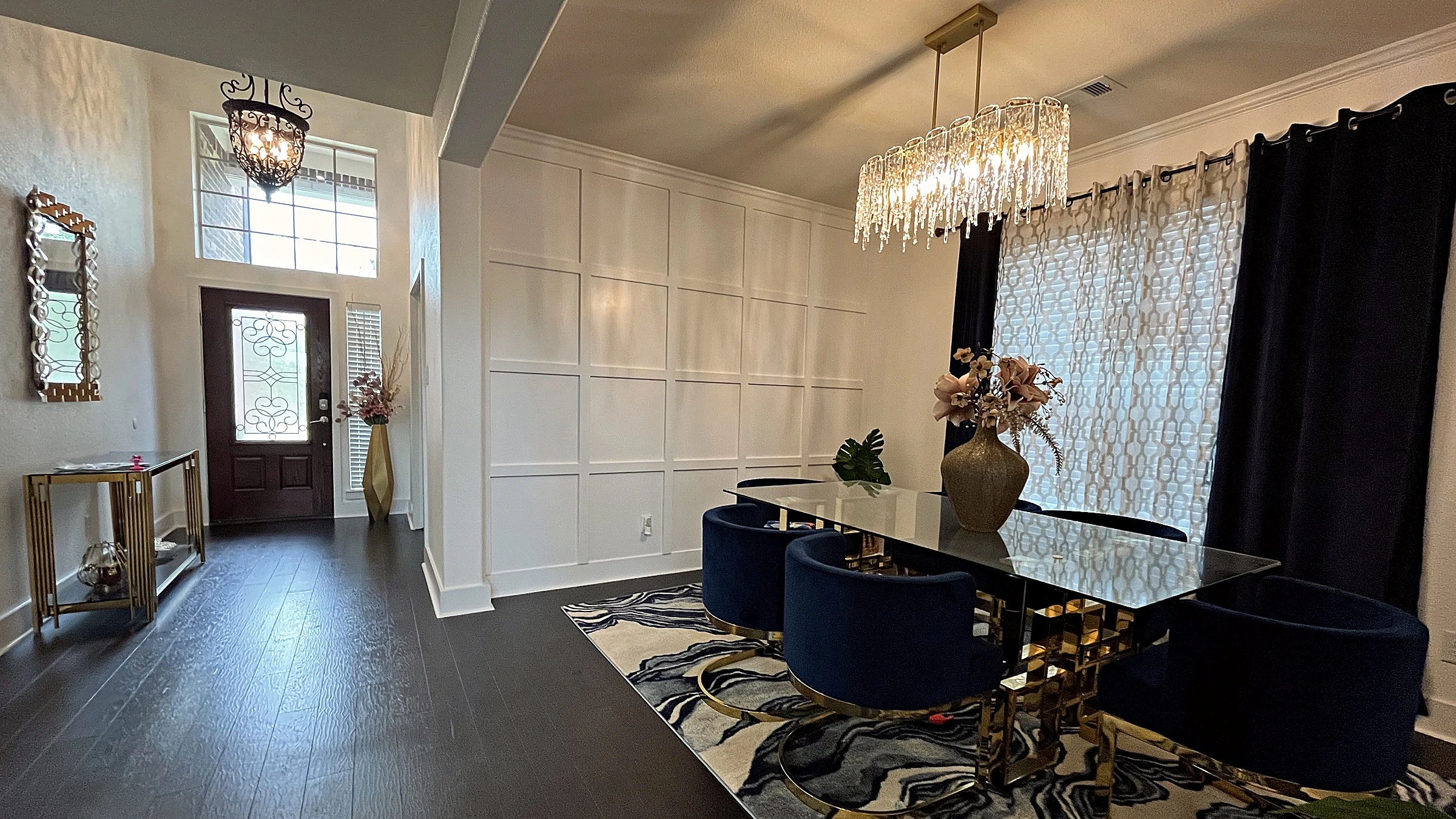 View from stair landing looking down over dark hardwood floors and open living room with amber tufted chairs