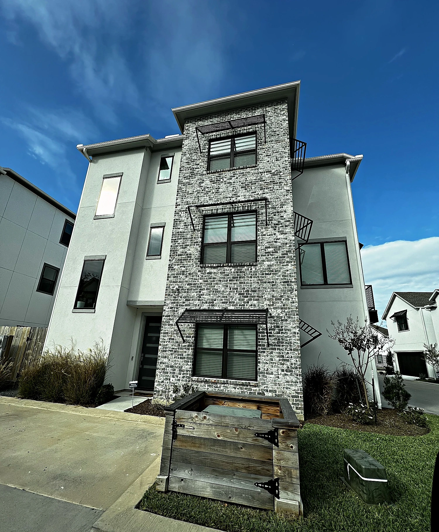 Spring Valley Village townhouse courtyard with dark-stained wood fencing, sculptural wall panels, and potted trees, Houston T