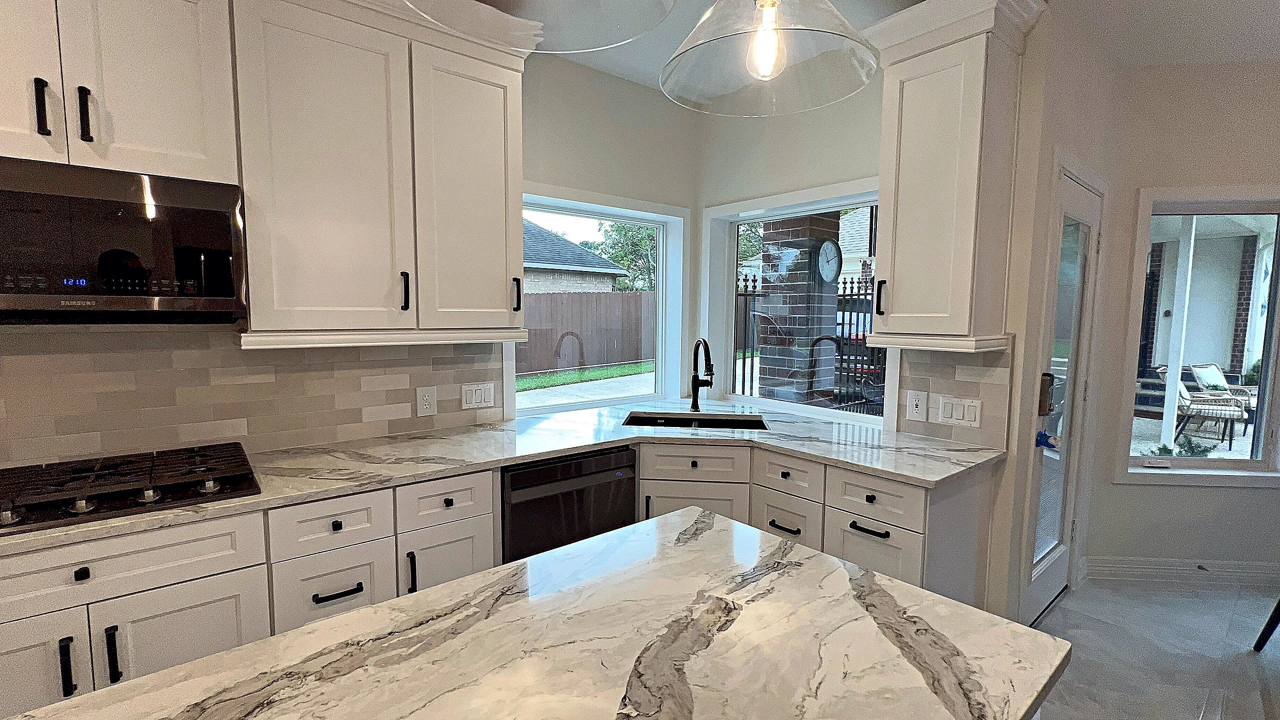 Completed Spring Valley Village kitchen remodel with natural stone surfaces, white cabinetry, and matte black accents by Bage