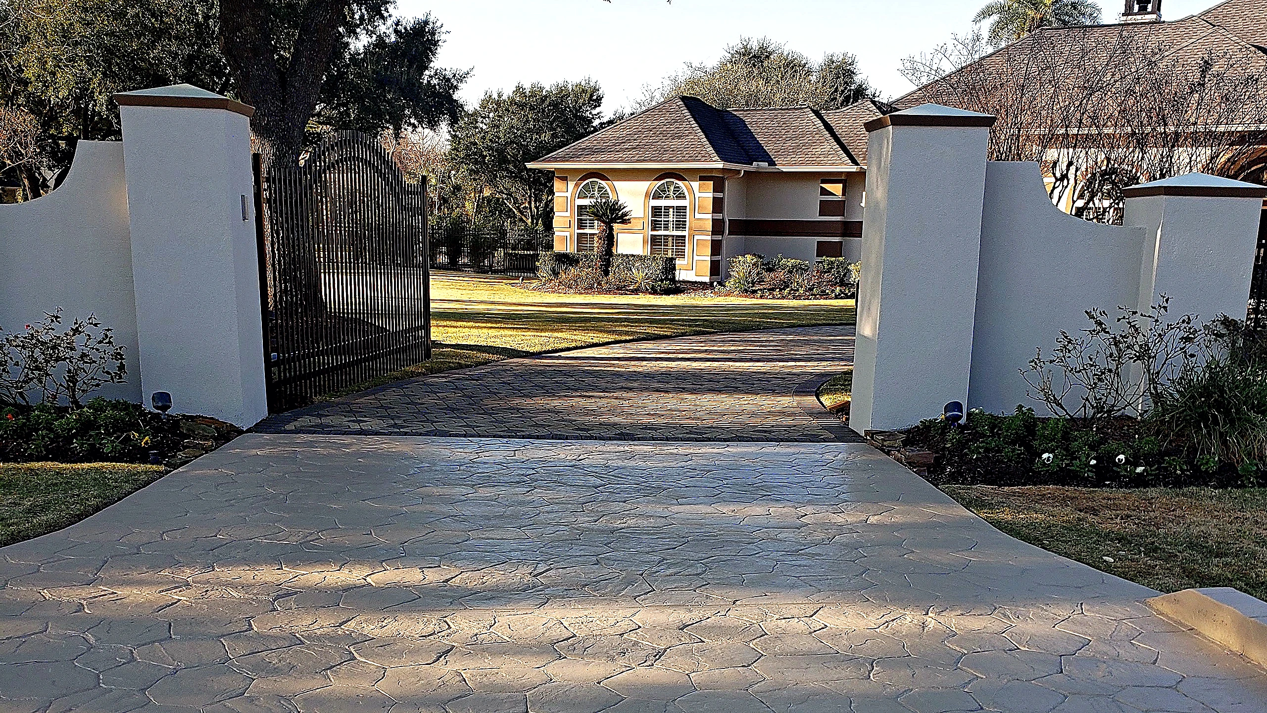 Stamped concrete driveway and rendered masonry gate columns marking the arrival to the renovated Tomball residence