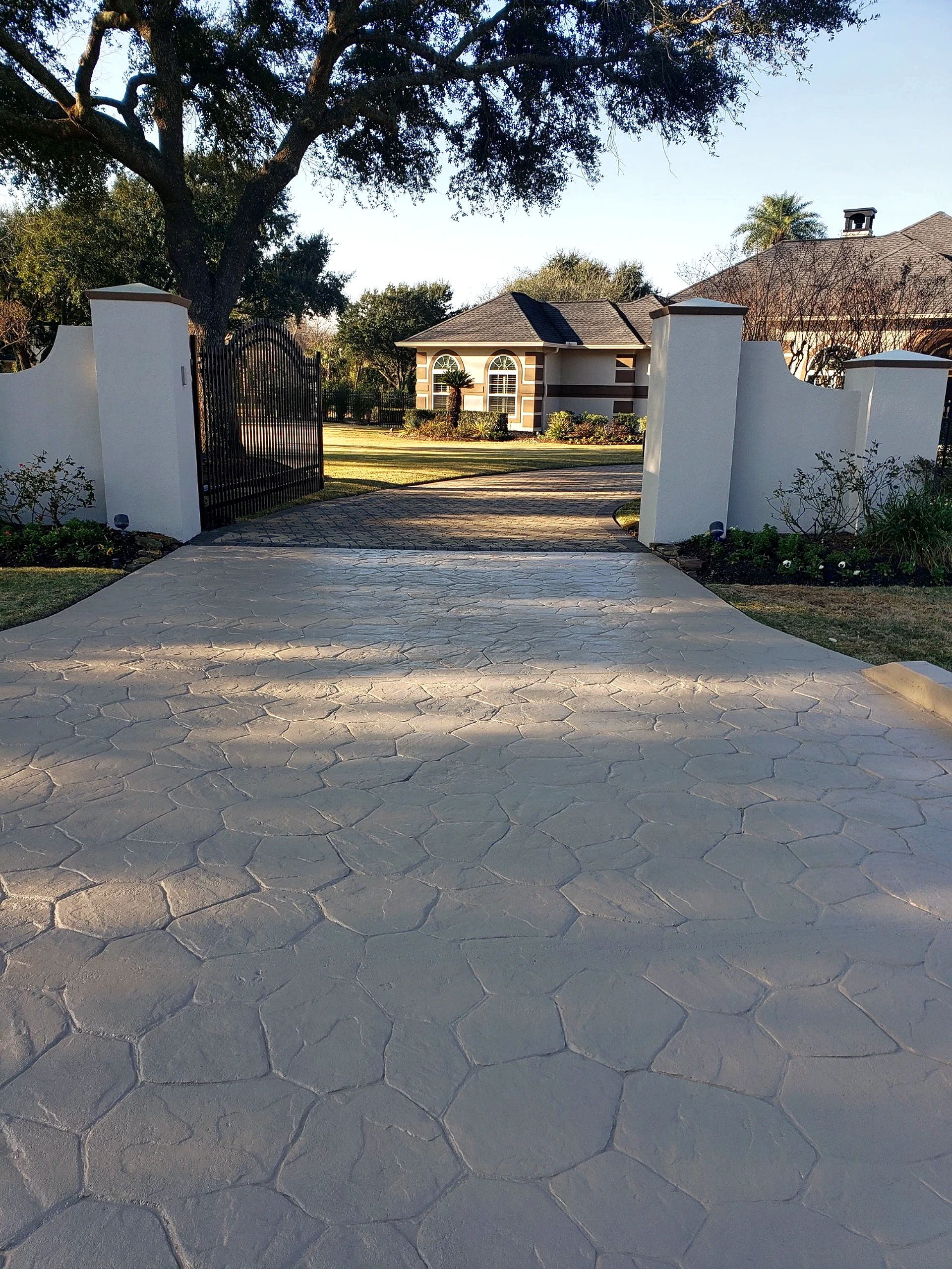Curving front driveway with paver border and landscaped beds at completed Tomball estate exterior renovation
